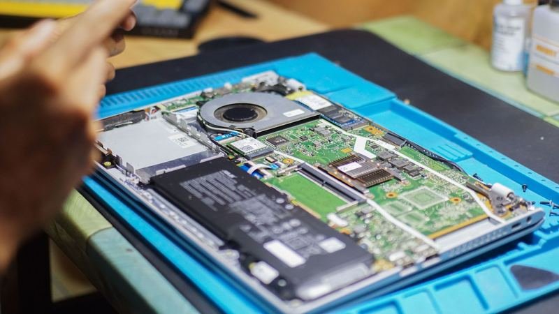 Technician repairing a laptop on a workbench